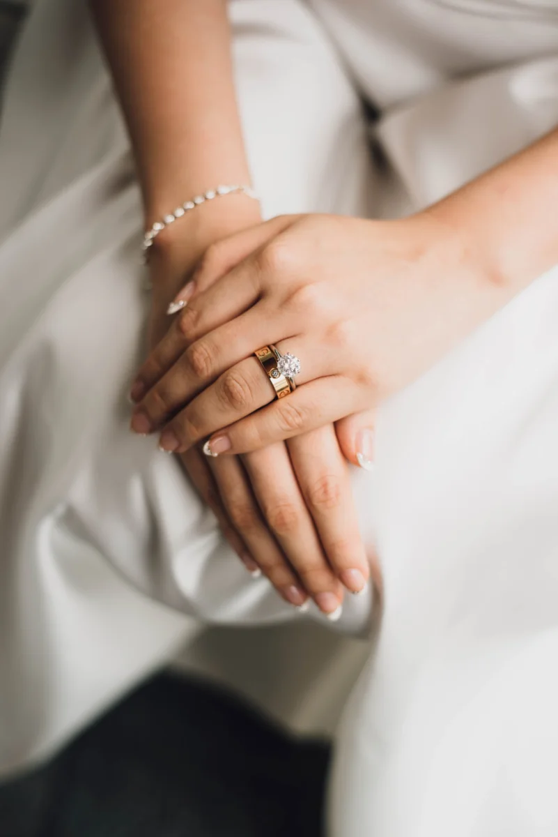 The bride's hands resting on her gown, an engagement ring and a fine bracelet.